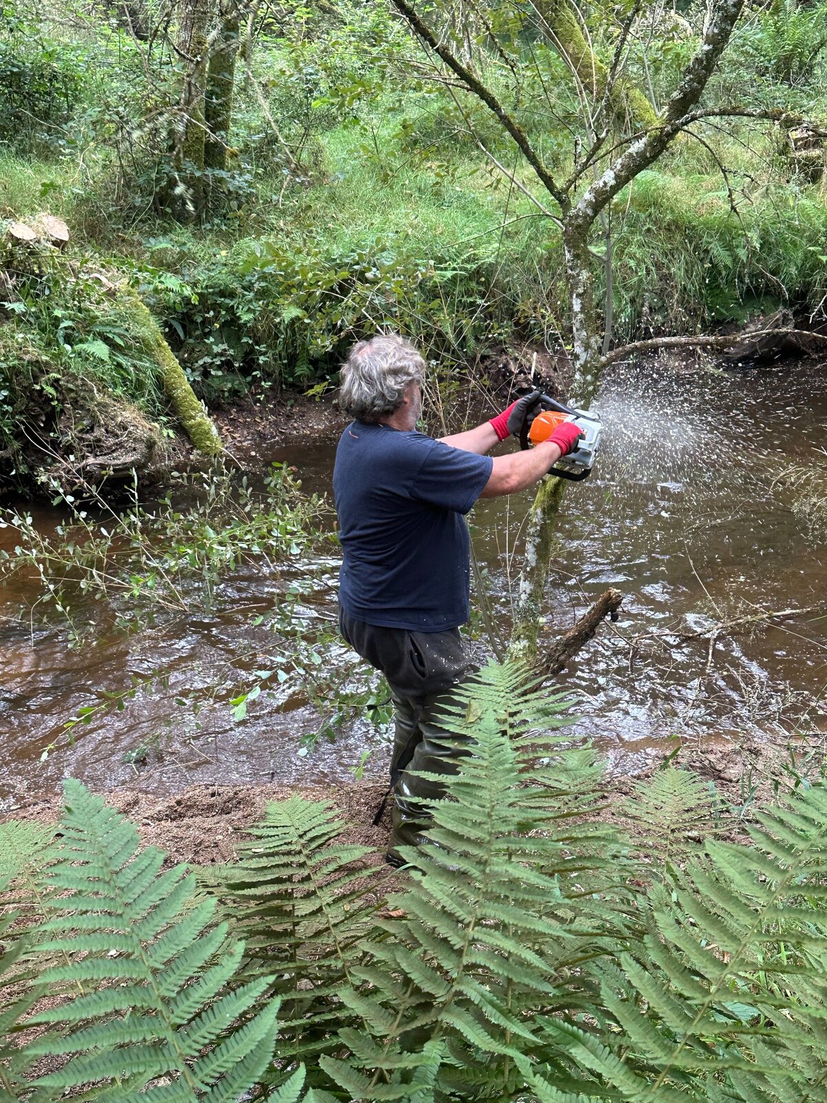 Un bénévole intervient dans le cours d’eau avec du matériel
