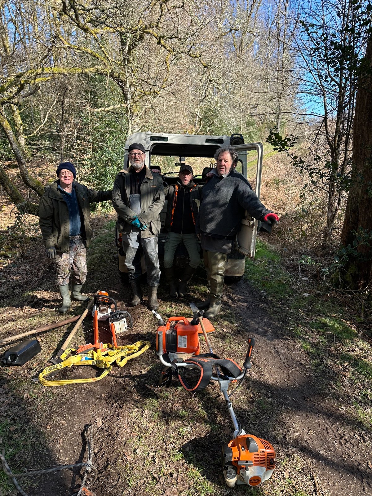 Quatre bénévoles avec leur matériel d’entretien, réunis dans un sous-bois